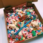 Assorted colorful candies in a pizza box with a checkered lining.